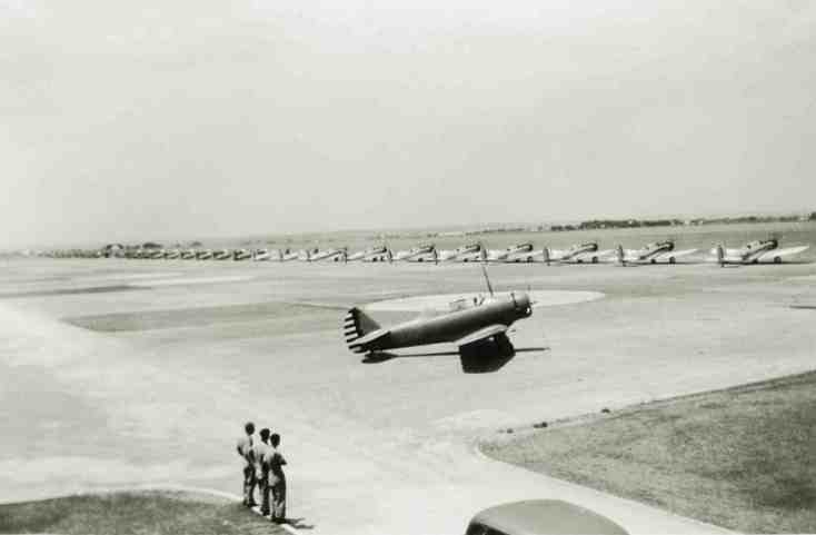 A BT-9 taxis along while airmen gaze at the distant A-12s and A-17s of the visiting 3rd Attack Group.